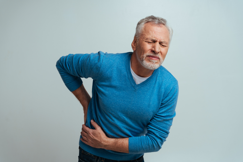 man with kidney stones holding lower back