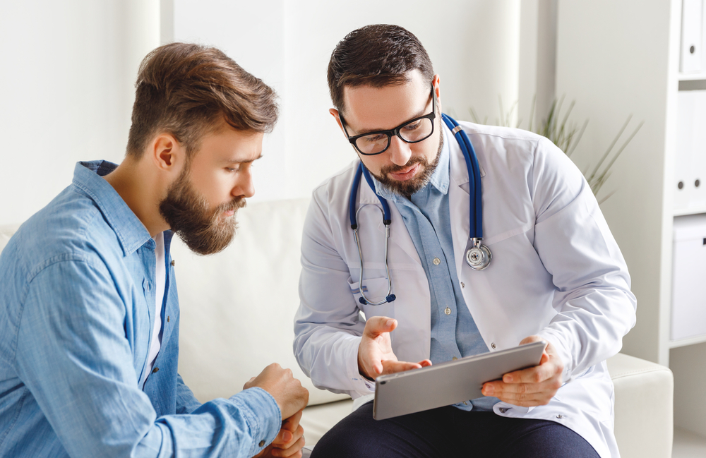 man talking with doctor while looking at chart.